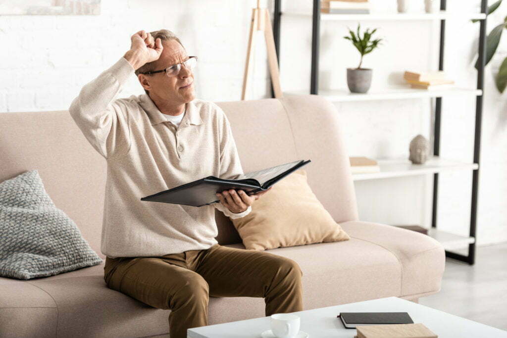 a man sitting on a couch and drinking from a glass of wine