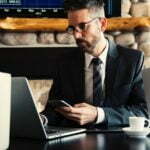 a man in a suit and tie sitting at a desk with a laptop