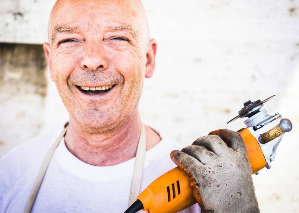 a man smiling and holding a drill