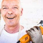 a man smiling and holding a drill
