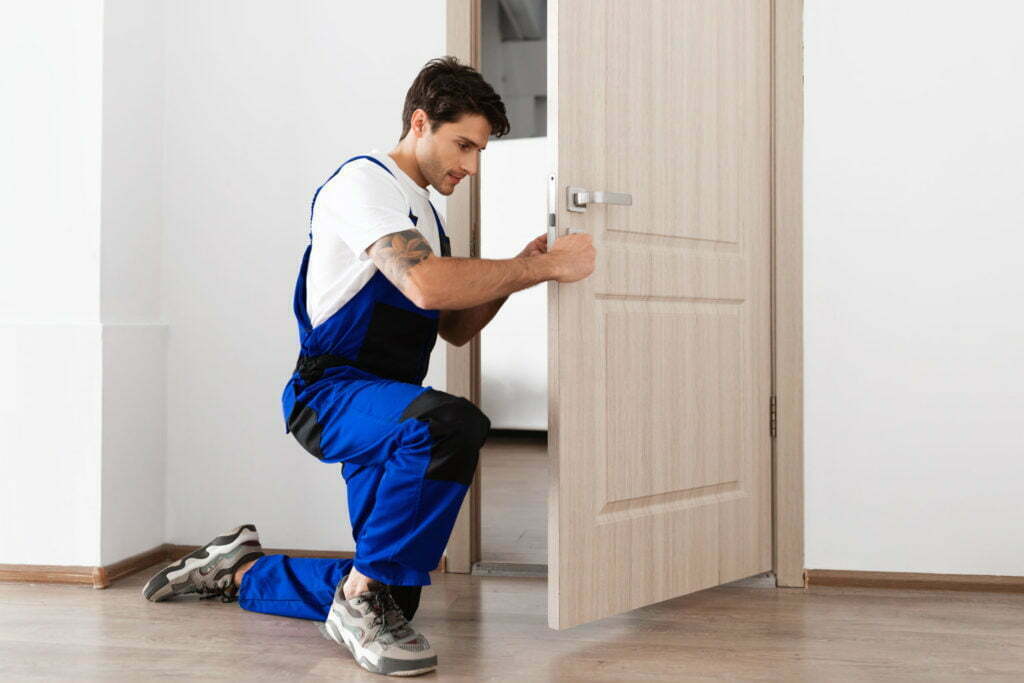 a man squatting down and holding a door open