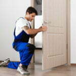 a man squatting down and holding a door open