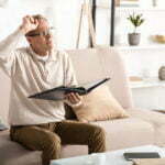 a man sitting on a couch and drinking from a glass of wine